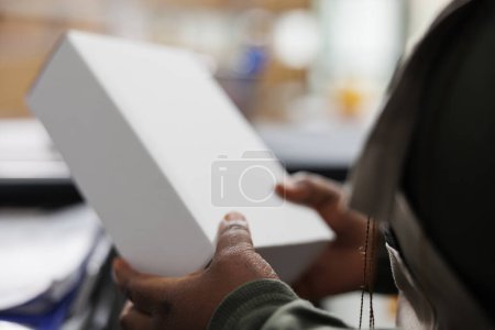 Photo for Stockroom employee holding white cardboard boxes, checking products before shipping packages in storehouse. Storage room manager working at clients orders during merchandise inventory - Royalty Free Image