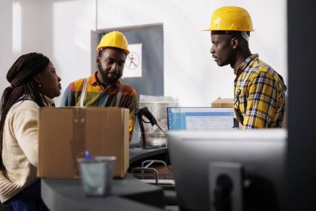 Photo for African american delivery service workers team discussing merchandise dispatching management at counter desk. All black men and woman warehouse employees register customer order parcel at reception - Royalty Free Image