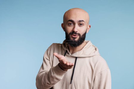 Photo for Arab man blowing air kiss with charming smile and looking at camera with flirty emotions. Romantic arabian bald bearded person expressing love and affection gesture studio portrait - Royalty Free Image