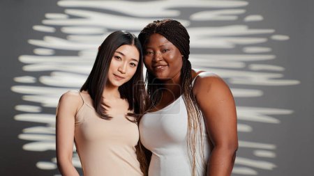 Photo for Group of friends expressing femininity in studio, filming beauty ad campaign and acting glamorous. Diverse skinny and curvy women with different skintones posing on camera, self love. - Royalty Free Image