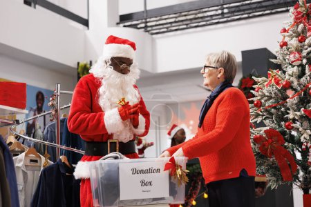 Photo for People filling out boxes for gifts to assist Santa Claus worker distribute Christmas spirit and donate to charities. Holiday generosity entails adults collecting clothes for children in need. - Royalty Free Image