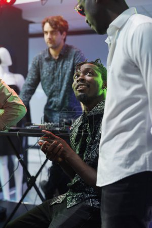 African american friends chatting while clubbing together in nightclub. Young men talking while resting near stage in club, relaxing at party and enjoying nightlife leisure activity
