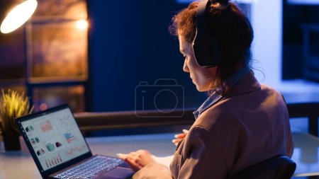 Photo for Careful manager analyzing e commerce diagrams report on laptop, typing financial report to increase profit. Young woman working at night time on investment plan with statistics and analytics. - Royalty Free Image