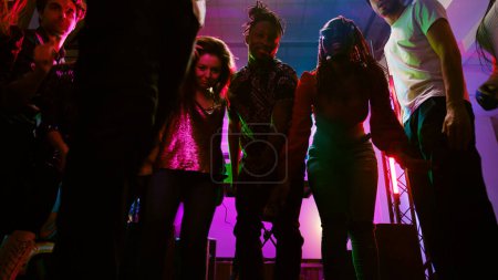 Téléchargez les photos : POV de personnes dansant lors d'une fête colorée, profitant de la soirée avec de la musique électronique disco dans une boîte de nuit. La foule des adultes s'amusent ensemble au spectacle moderne, se sentant funky. Coup de main. - en image libre de droit