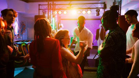 Foto de POV de gente funky bailando y sintiéndose feliz en el club, disfrutando de una fiesta moderna con luces de discoteca y espectáculo en vivo. Grupo de personas de fiesta en el club nocturno, moviéndose en la pista de baile. Disparo de mano. - Imagen libre de derechos