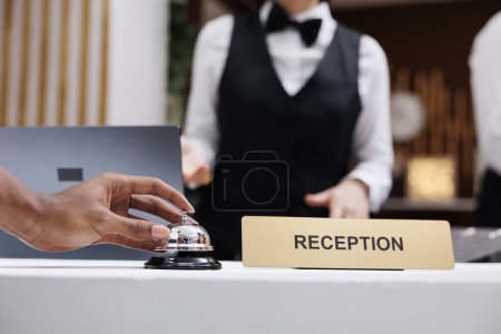 Photo for Tourist using service bell at front desk, ringing bell to talk to receptionist in lobby and check in. Hotel guest at reception counter receiving luxury assistance with room accommodation. Close up. - Royalty Free Image