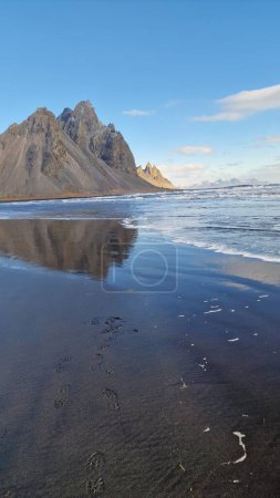 Photo for Stone mountain crests meeting the ocean in fantastic icelandic environment with natural black sand beach. Nordic stokksnes peninsula with vestrahorn mountain chain and beachfront, sightseeing. - Royalty Free Image