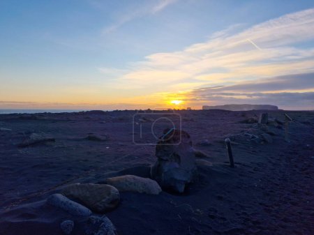 Téléchargez les photos : Superbe vue sur les hauts plateaux au coucher du soleil dans la région nordique avec des plages couvertes de gel et des pâturages gelés à distance. Route pittoresque au bord de la route avec des paysages nordiques de falaises et de terres agricoles en Islande. - en image libre de droit