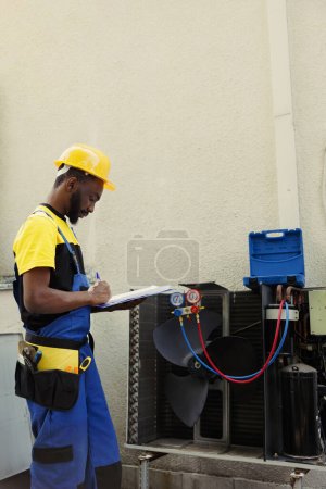 Photo for Certified technician doing inspection of freon levels and necessary repairs to prevent major breakdowns. Seasoned mechanic troubleshooting hvac system, writing findings on clipboard - Royalty Free Image
