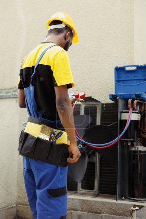 Photo for Precise serviceman doing annual condenser maintenance, assembling pressure measurement device before starting work. Seasoned wireman checking refrigerant leaks leading to reduced cooling efficiency - Royalty Free Image