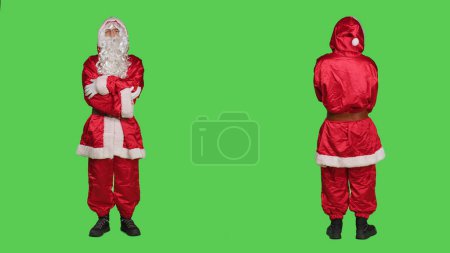 Photo for Saint nick laughing on camera, posing in red costume over full body greenscreen. Santa cosplay spreading christmas eve holiday spirit, portraying famous winter character with hat and glasses. - Royalty Free Image