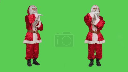 Photo for Saint nick feeling exhausted in studio, showing timeout symbol to express burnout while he is overworked. Winter festive character in red costume being tired, rejecting work on greenscreen. - Royalty Free Image