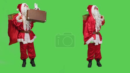 Foto de Santa Claus autostop con maleta y regalos en saco rojo, difusión espíritu víspera de Navidad y positividad. Persona actuando como santa Nick llevando regalos y maletín para entregar juguetes. - Imagen libre de derechos
