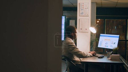 Photo for Revealing shot of employees checking company figures, postings and documents for accuracy during nighshift. Staff member working overnight, analyzing stored computerized financial information - Royalty Free Image
