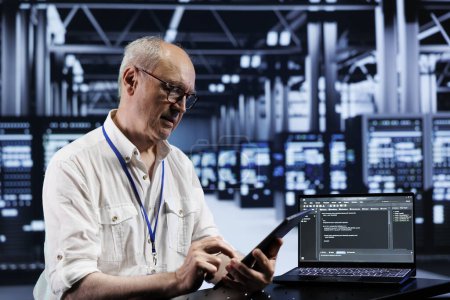 Photo for Senior engineer coding in high tech data center using javascript language. Expert updating software on server rigs on laptop terminal, ensuring optimal performance and security - Royalty Free Image
