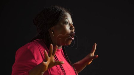 Foto de Retrato de vista lateral de una afro-americana irritada vestida con suéter rosa y tocándose la cabeza. Enojada joven negra gritando no a la cámara mientras está de pie contra un fondo aislado. - Imagen libre de derechos