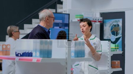 Photo for Aged client in need of prescription illness prevention drug informations in apothecary, asking knowledgeable druggist. Pharmacy employee helping older customer with medical expertise - Royalty Free Image