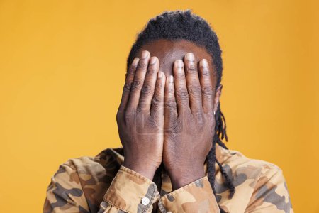 Photo for Young adult showing three wise monkeys gesture on camera, covering eyes, mouth and ears as wisdom sayings. African american man advertising silence concept in studio over yellow background - Royalty Free Image