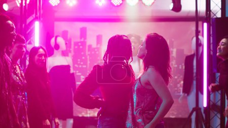 Photo for Young adults dancing on cool beats, men and women preparing for dance battle at nightclub. Group of people having fun showing off modern funky moves and skills, enjoying party. Tripod shot. - Royalty Free Image