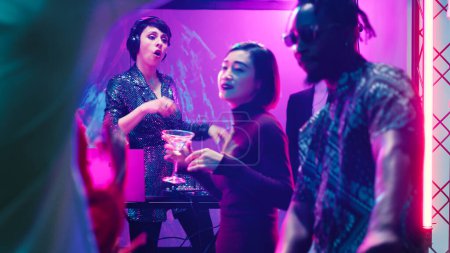 Photo for Cool woman DJ mixing music on stage at party, dancing with group of people at audio panel station. Young person partying with friends, enjoying night out at discotheque event. - Royalty Free Image