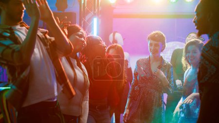 Téléchargez les photos : Les jeunes adultes s'amusent à danser à la fête, à profiter de la bataille de breakdance avec un groupe d'amis sur la piste de danse. Les gens exhibant des mouvements de danse et sautant dans la discothèque, la vie nocturne. - en image libre de droit