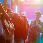 Young adults having fun dancing at party, enjoying breakdance battle with group of friends on dance floor. People showing off dance moves and jumping around in discotheque, nightlife.