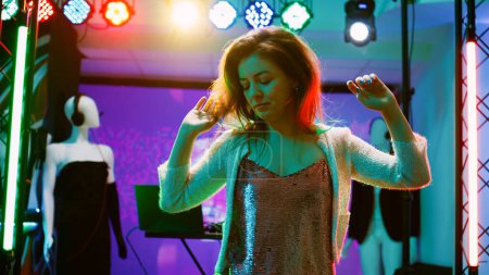 Photo for Young person dancing at nightclub, showing cool dance moves in discotheque with funky music. Cheerful girl partying and having fun at electronic party, stage lights on dance floor. Handheld shot. - Royalty Free Image