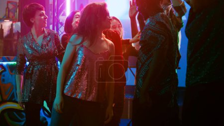 Photo for Group of people dancing at disco party, having fun together with breakdance battle at club. Friends showing off funky moves for dance battle on dance floor, partying in discotheque. - Royalty Free Image