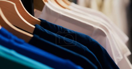 Photo for Selective focus of hangers and racks filled with basic shirt, empty modern boutique with fashionable clothes. Shopping centre equipped new fashion collection waiting for customers. - Royalty Free Image