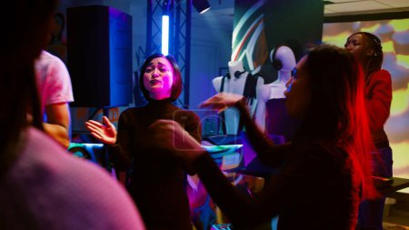 Téléchargez les photos : Les jeunes dansent au club, s'amusent à la fête disco sur la piste de danse avec une musique funky. Groupe joyeux d'amis appréciant le rassemblement social à la discothèque, lumières colorées. Coup de main. - en image libre de droit