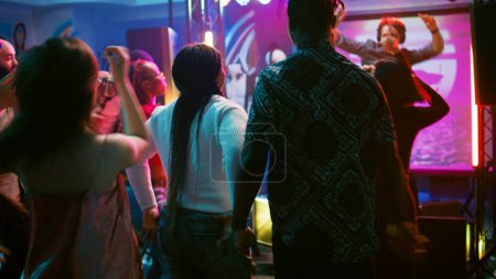 Photo for Diverse people enjoying night at club, dancing on electronic music and having fun. Group of friends feeling cheerful and showing cool funky moves on dance floor, partying. Handheld shot. - Royalty Free Image