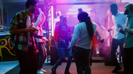 Téléchargez les photos : Danseuse faisant la fête à la boîte de nuit, montrant des mouvements de danse funky sur la musique électronique à la fête. Les jeunes s'amusent avec des lumières disco sur la piste de danse, célébration. Coup de main. - en image libre de droit