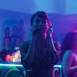 Woman answering phone call at party in the club, trying to have conversation with loud music on dance floor. Young adult using mobile phone remote chat at clubbing event, entertainment.