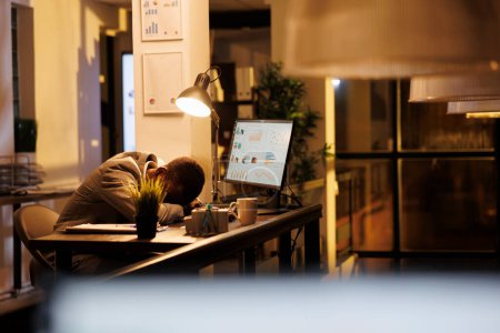 Téléchargez les photos : Fatigué vidé entrepreneur dormant sur le bureau de démarrage, employé bourreau de travail s'endormir après avoir terminé le rapport financier. Travailleur afro-américain épuisé avec le syndrome du burnout se reposant à - en image libre de droit