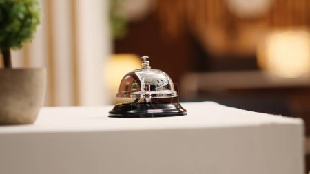 Photo for Extreme close up of concierge bell next to mini plant on cozy hotel lounge check in desk. Elegant service bell on modern stylish hospitality industry resort reception counter - Royalty Free Image