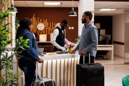 Check-in wait time and guest satisfaction. Young African American couple arriving at all-inclusive honeymoon resort, tourists waiting for booking confirmation at hotel reception