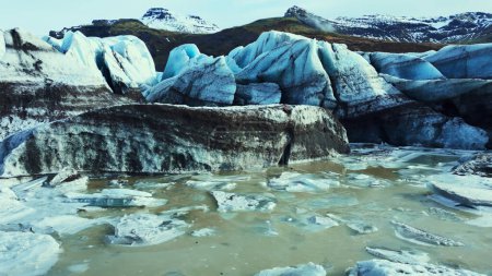 Beautiful vatnajokull glacier drone shot, massive ice blocks and icebergs with blue color. Spectacular icelandic glacier lagoon with snowy mountains and fantastic frozen rocks. Slow motion.