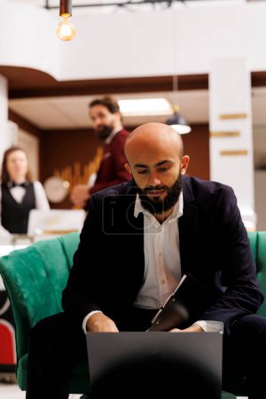 Photo for Corporate professional in lounge area waiting to meet with business CEO to discuss new colllaboration for growth. White collar worker travelling for work, using laptop in hotel lobby. - Royalty Free Image