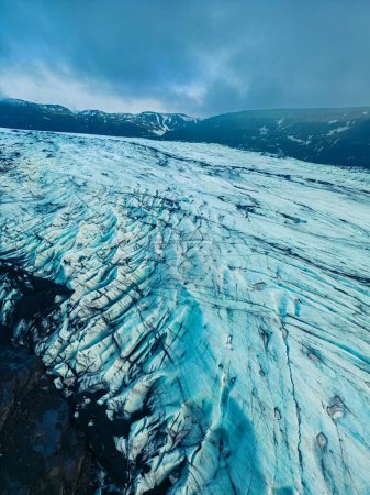Aerial view of vatnajokull glacier mass in iceland, beautiful ice rocks with massive crevasse around snowy hills and scenery. Majestic frozen icebergs floating on freezing cold lake.
