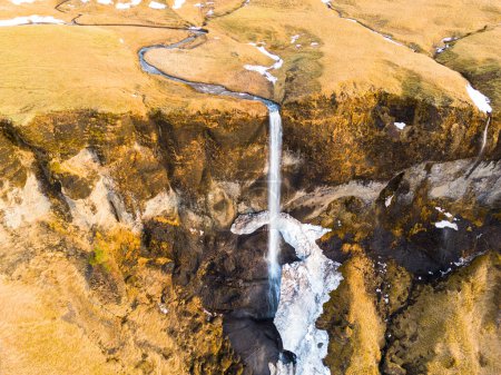 Foto de Drone shot of natural foss a sidu waterfall, huge water stream falling off covered frost edges. Islandés espectacular cascada corriendo por colinas de montaña congeladas en la región nórdica. - Imagen libre de derechos