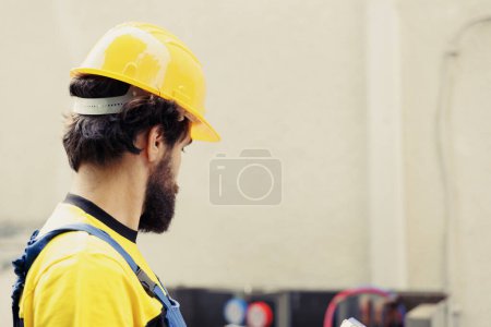 Photo for Certified repairman commissioned for outdoor air conditioner annual checkup, writing report on clipboard. Skilled engineer doing hvac system inspection and safety check, looking for refrigerant leaks - Royalty Free Image