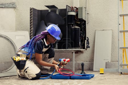 Photo for Qualified engineer commissioned by home owner, preparing for annual air conditioner maintenance. Competent mechanic unpacking toolkit with professional equipment needed to fix faulty draining lines - Royalty Free Image