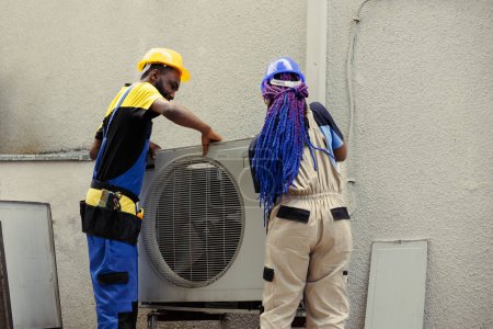 Téléchargez les photos : Réparateurs experts afro-américains séparant le panneau de climatiseur avec des techniques et des équipements industriels pour réparer les filtres à air, les problèmes de système électrique et les bobines d'évaporateur gelées - en image libre de droit