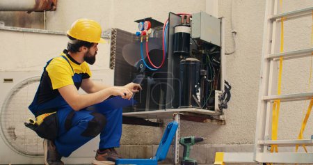 Knowledgeable professional filling out revision of insurance contract for customer to sign after finishing repairments on condenser. Capable specialist writing down cost of fixed internal components