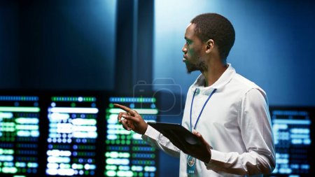 Afrikanisch-amerikanischer Spezialist nutzt Tablet, um Datencenter-Sicherheitsfunktionen zu überprüfen, die vor unbefugtem Zugriff, Datenverletzungen, DDoS-Angriffen und anderen Bedrohungen der Cybersicherheit schützen
