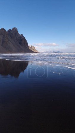 Masivas montañas de vestrahorn conectan con el océano, fantástico entorno nórdico con una playa de arena negra única. Islandia stokksnes península con enormes acantilados y colinas, impresionante ruta panorámica.