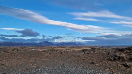 Majestuoso paisaje de carretera en el campo ártico con tierras de cultivo y colinas nevadas en la distancia, paisaje natural icelandés. Espectacular naturaleza salvaje en ambiente nórdico, ruta escénica.