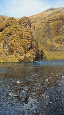 Téléchargez les photos : Débit spectaculaire de la rivière près des bords bruns, paysage naturel dans la région nordique avec de l'eau coulant du sommet gelé de la montagne. Nature majestueuse en pleine nature glacée, paysages nordiques. - en image libre de droit