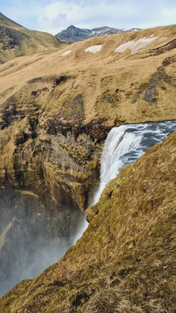 Téléchargez les photos : Magnifique cascade de skgafoss nordique avec cours d'eau coulant sur les bords de la colline, cascade glaciaire avec écoulement de la rivière qui tombe. Belle nature sauvage nordique présentant un paysage naturel. - en image libre de droit