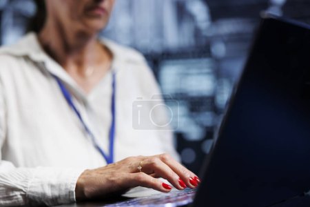 Photo for Elderly IT expert in server hub using laptop ensuring valuable data remains shielded from potential threats, safeguarding against unauthorized access and vulnerabilities, close up - Royalty Free Image